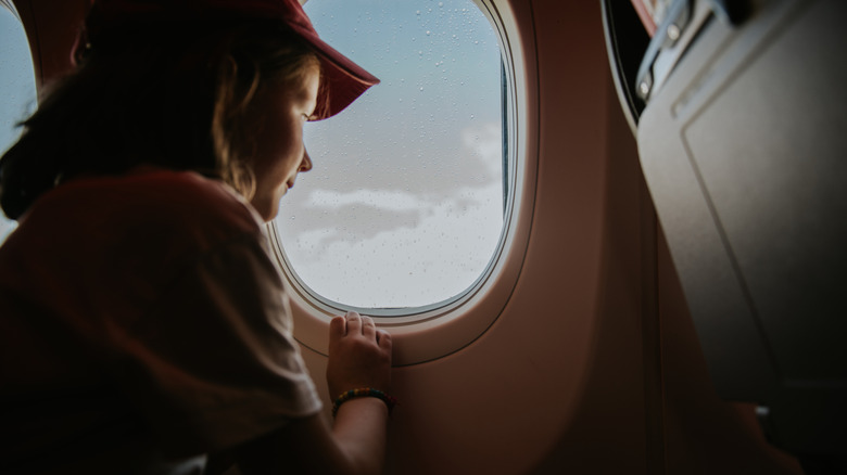 A young passenger looks out of a window on an airplane