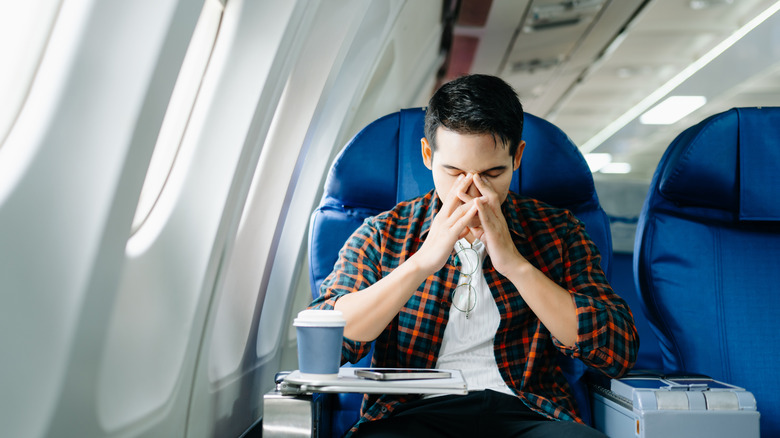 Person holding their head on an airplane