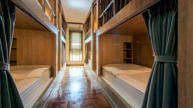 Hostel dormitory beds with privacy curtains arranged in dorm room