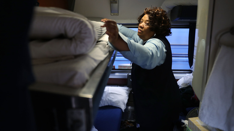 An Amtrak attendant makes up a bed in a roomette.