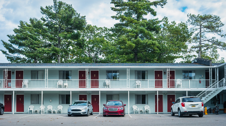 A two-storey motel features a parking lot for cars to park right outside the guest rooms