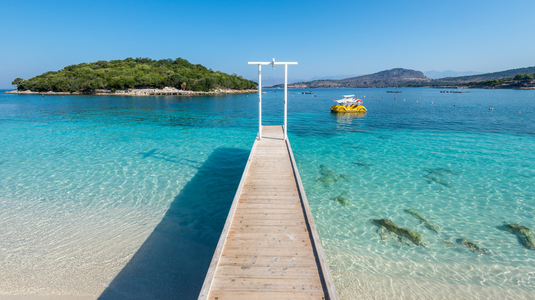 Blue waters of Bora Bora Beach in Ksamil in Albania, with a small boardwalk stretching into the water