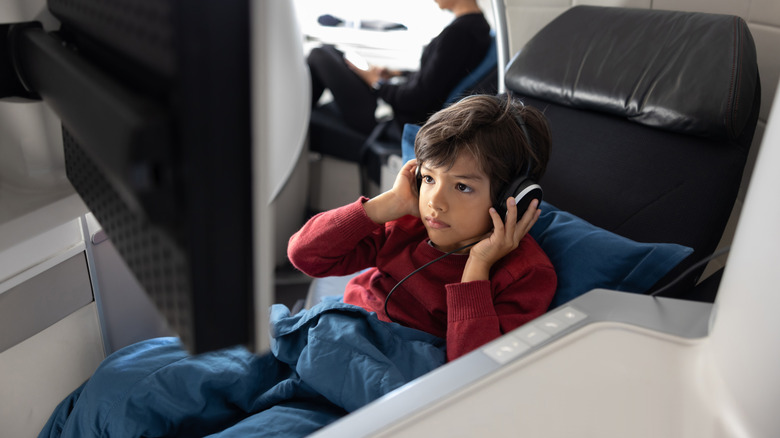 Young boy with earphones in a lie-flat business class seat