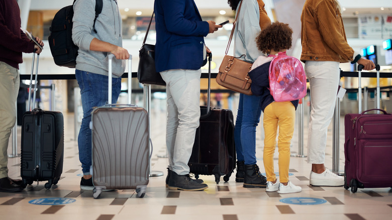 Adults and a child with their luggage queuing at the airport
