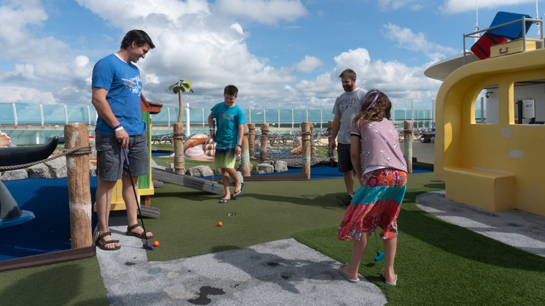 Family plays putt putt golf while on a cruise