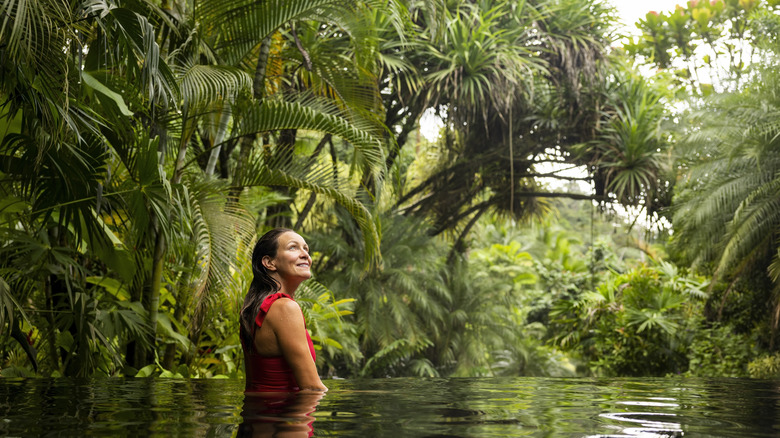 Traveler wading through a lush jungle pond
