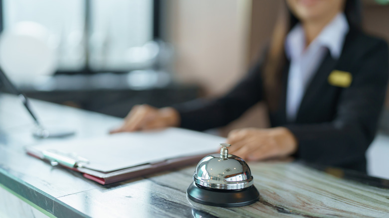 A blurred out concierge at a hotel desk with a silver bell on it.