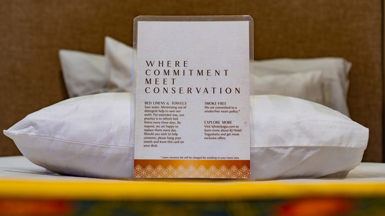 A conservation commitment and notice in a hotel room propped up on a pillow