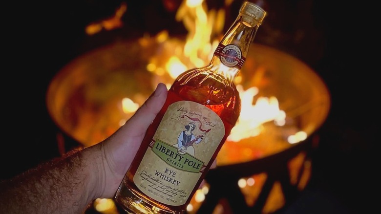 Liberty Pole Spirits rye whiskey bottle held in front of fire