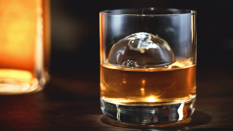Glass of whiskey with large round ice cube