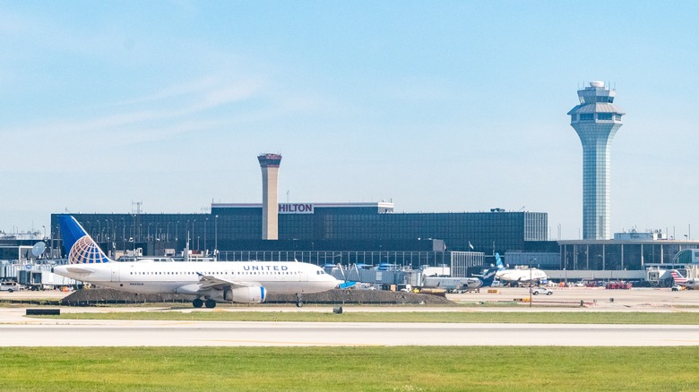 A United airplane on the runway with an air traffic control tower in the background