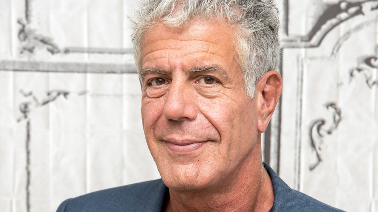 Anthony Bourdain looks to side small smile white background