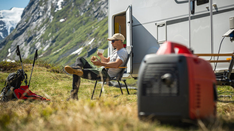 Person sitting next to an RV with a generator in the foreground