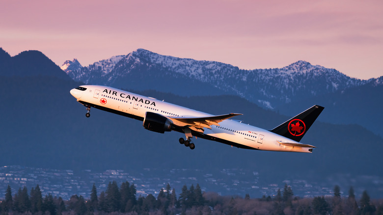Air Canada plane takes off at sunset with mountains in background
