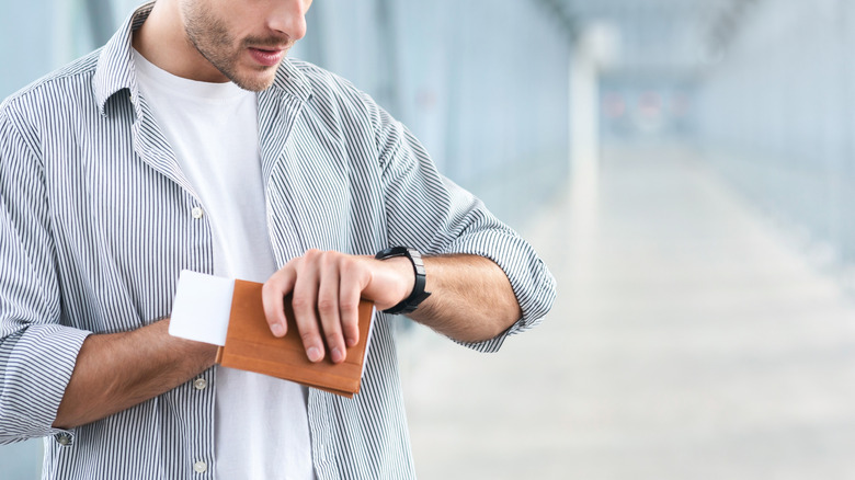 A man checks his wristwatch at the airport