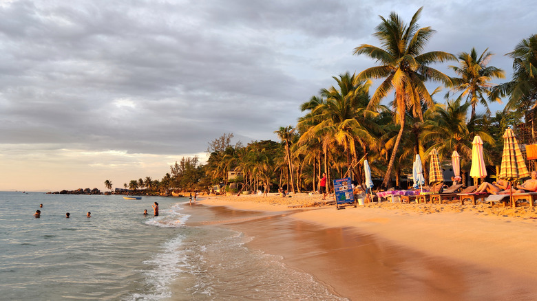 People lounge and swim in the water on a cloudy day at Phú Quốc's Long Beach