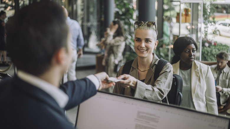 A person checking into a hotel while handing over a credit card to the concierge