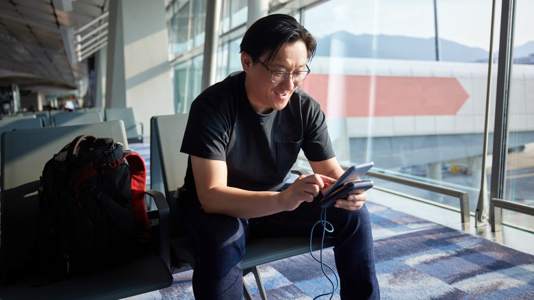 Man using a power bank to charge a phone at the airport
