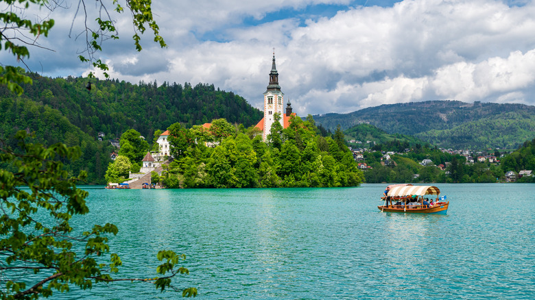 A boat paddles on Lake Bled in front of its picturesque island in Slovenia