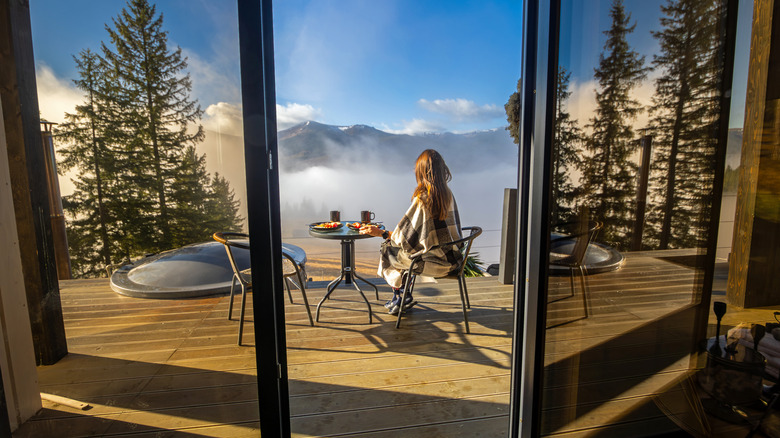 A woman has breakfast on a terrace overlooking the mountains