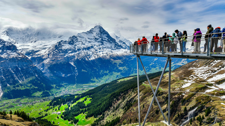Tourists at an observation deck in Grindelwald, Switzerland viewing the Alps