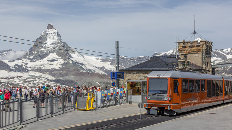 Tourists at a train station in Switzerland with the Matterhorn in background