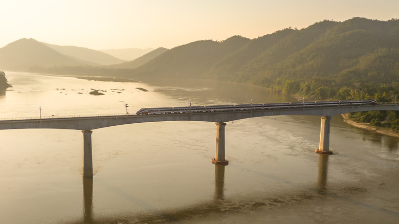 A Laos-China Railway train crossing the Mekong River on a railway bridge.