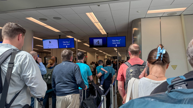 Queues of people at an airport security area.