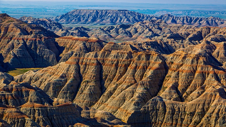 Early morning sunlight casts orange and yellow light across the extreme rock formations and canyons of Badlands National Park