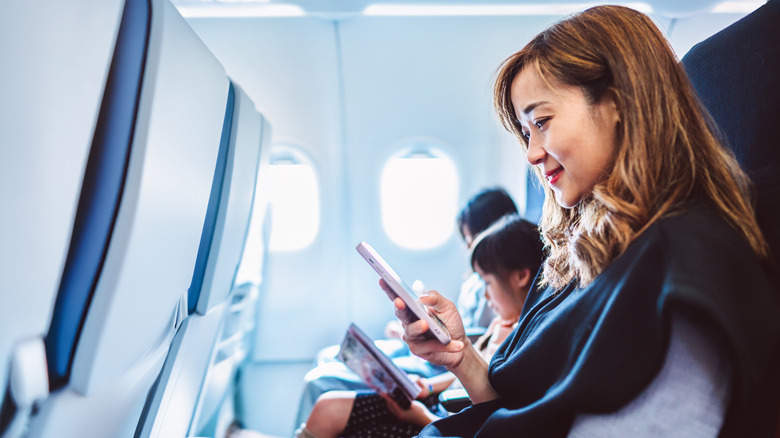 A traveler using her phone on an airplane