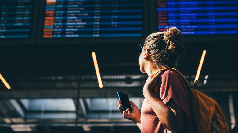 A traveler looks at departure board at airport