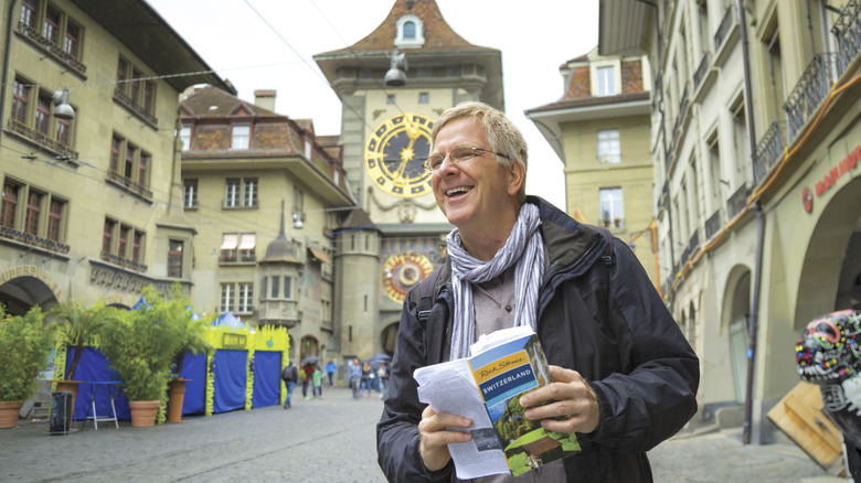 Smiling Rick Steves holding a guidebook in Bern, Switzerland.