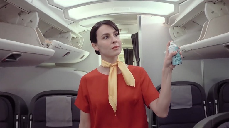 Flight attendant spraying pesticide spray bottle in cabin