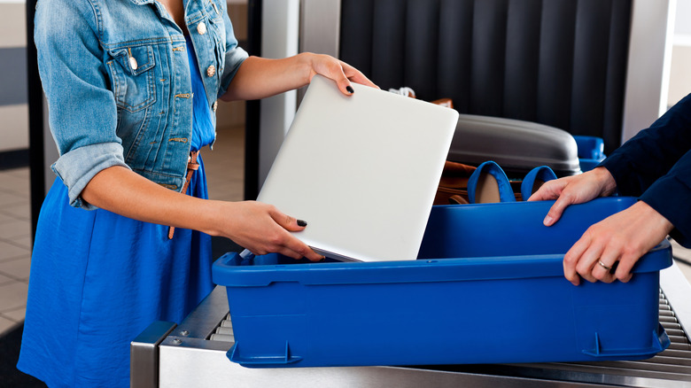 Woman taking her laptop out at airport checkpoint