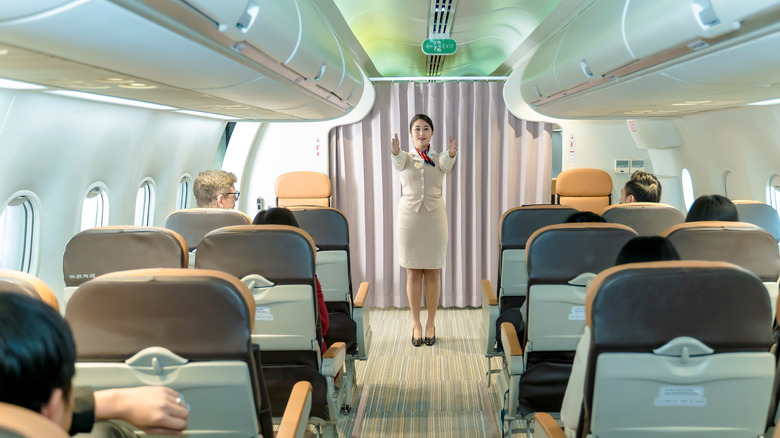 A flight attendant demonstrates brace position