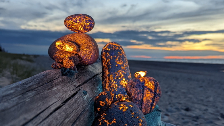 Glowing Yooperlite orange rocks against sandy beach