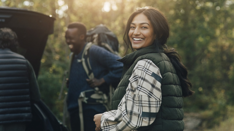 Friends camping together packing up a car in the woods