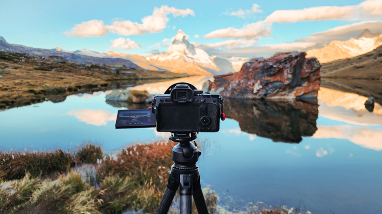 A mirrorless camera set up on a tripod in front of Stellisee Lake capturing Matterhorn mountain in Zermatt, Switzerland, with the reflection of the blue sky in the calm waters below