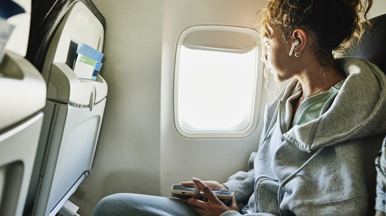 Girl sitting on a plane wearing hoodie