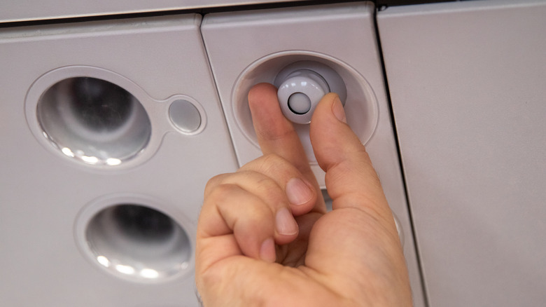 Hand closing an air vent on a plane