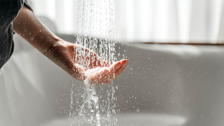 Person testing water temperature in the shower