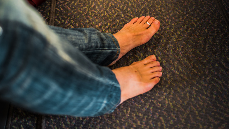 Bare feet on the carpet in the aisle of a plane.