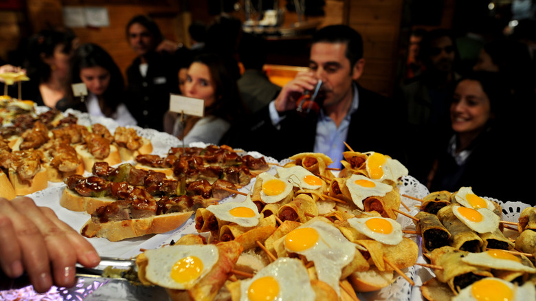 Diners standing in front of a countertop filled with tapas dishes