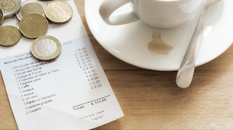 Coins, coffee cup, and Italian bill on a table