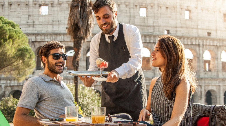 Italian waiter serving ice cream to a couple in Italy