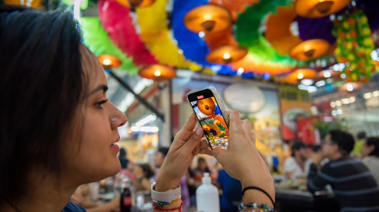 Woman takes a photo of decorations at an Oaxacan market