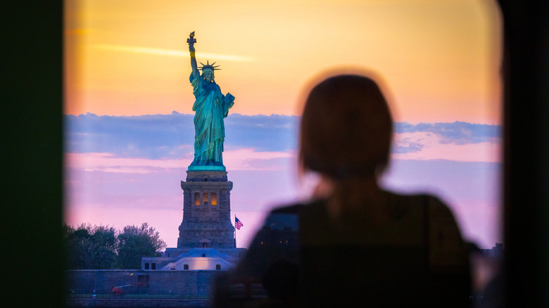 A young woman looking at the Statue of Liberty, New York