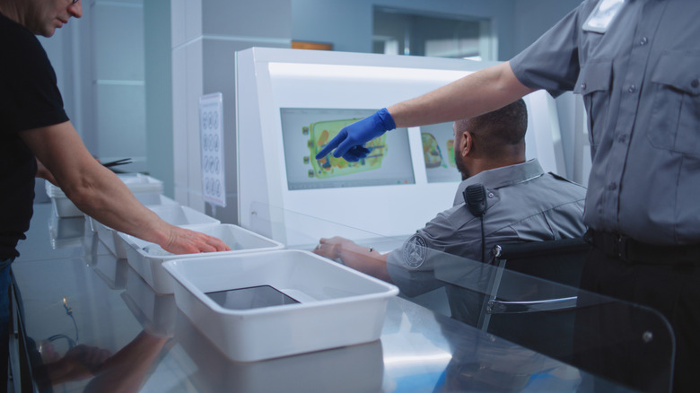 Traveler placing tablet and other electronics in TSA plastic tray