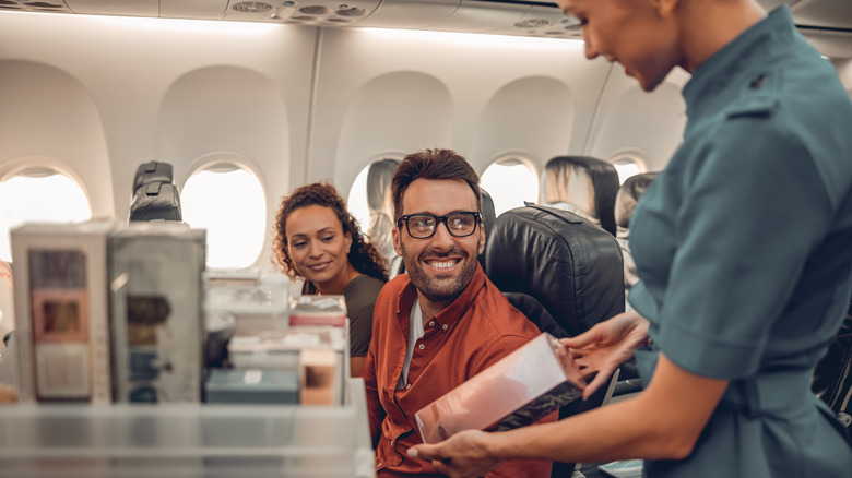 Flight attendant serving drinks to passengers