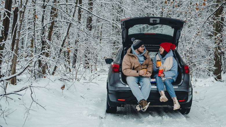 Couple sitting in the open trunk of their car in winter